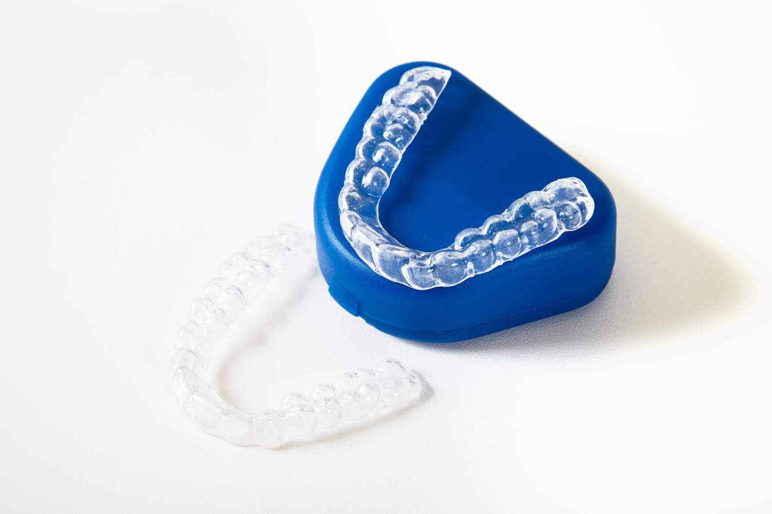 Placas de alinhadores transparentes com estojo azul em fundo branco para tratamento com aparelho Invisalign na Tijuca.